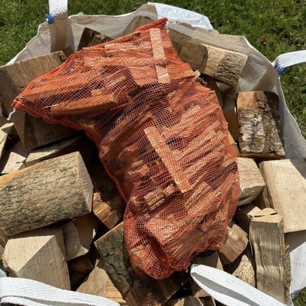Netted kindling bag on top of dumpy bag of kiln-dried firewood